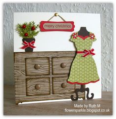 a handmade christmas card with an image of a dress on a dresser and a potted plant