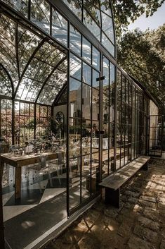 the inside of a glass house with tables and chairs in it's patio area