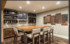 a kitchen with a wooden table surrounded by white chairs and bar stools next to it