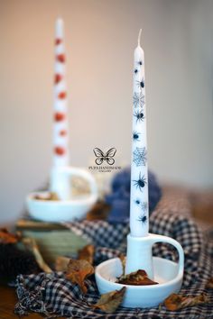 two white candles sitting on top of a wooden table next to dishes filled with food