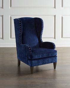 an upholstered blue chair in front of a white wall