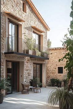 an outdoor patio with tables and chairs next to a stone building that has two balconies on the second floor