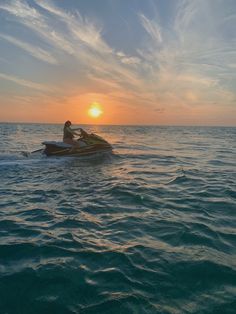 two people on a jet ski in the ocean at sunset