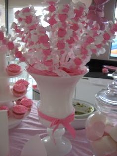 a vase filled with pink and white cupcakes on top of a purple table cloth