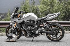 the motorcycle is parked on the side of the road near some trees and mountains in the background