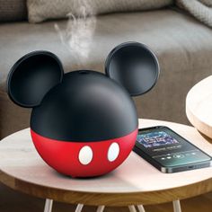 a red and black mickey mouse speaker sitting on top of a table next to a cell phone