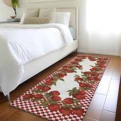 a white bed sitting next to a red checkered rug on top of a wooden floor