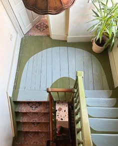 an overhead view of a staircase with green painted walls and wooden steps leading up to the second floor