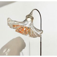 a lamp that is sitting on top of a metal stand with a glass flower in it