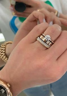 a woman is holding two different rings on her hand and looking at the watch in front of her