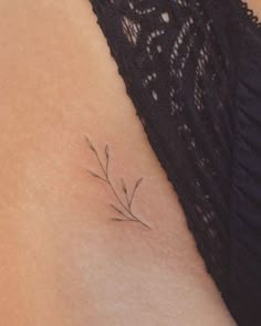 a small flower tattoo on the back of a woman's left upper arm and shoulder