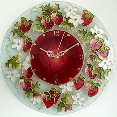 a glass clock with strawberries and flowers painted on the face is hanging from a wall