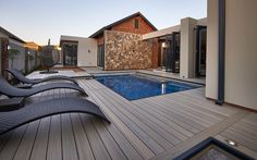 an outdoor swimming pool with chaise lounges next to it and a house in the background