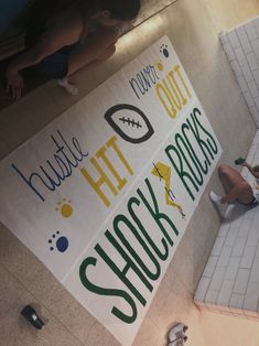 a woman sitting on the floor in front of a sign that reads, football hit out sucks