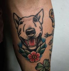 a dog tattoo on the leg of a person's arm with flowers around it