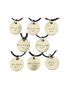 six personalized hand stamped necklaces with names on the front and back, hanging from black cord