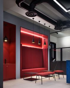 an office with red and grey walls, black ceiling lights and chairs