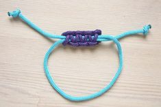 a blue and purple bracelet with the word love on it sitting on top of a wooden table