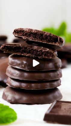 chocolate cookies stacked on top of each other next to some mint leaves and green leaves