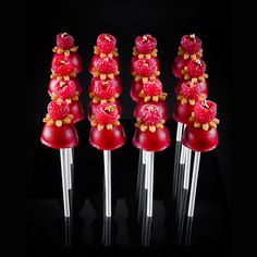 four pieces of fruit are arranged on clear acrylic sticks with candy toppings