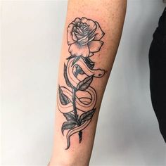 a woman's arm with a rose and snake tattoo on the left inner forearm