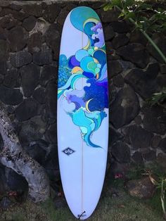 a surfboard is leaning against a stone wall with an image of a woman on it