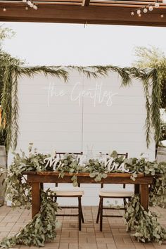 the table is set with greenery and chairs for guests to sit down at it