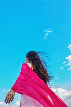 a woman with long hair wearing a pink and white sari, looking up into the sky