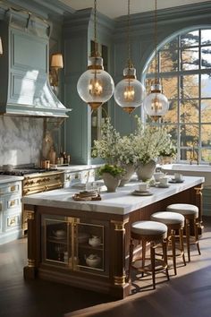 a large kitchen with marble counter tops and gold trimming on the cabinets, along with two chandeliers hanging from the ceiling