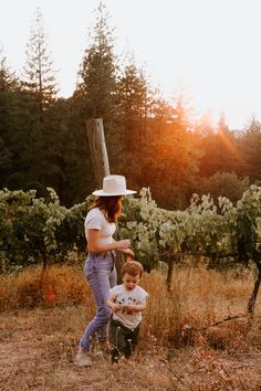 a woman standing next to a little boy in a field