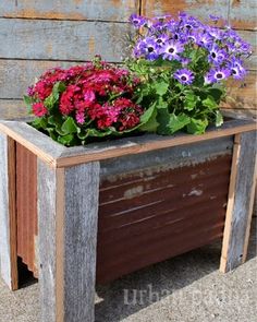 a wooden planter filled with purple and red flowers