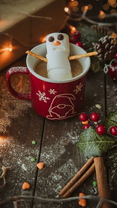 a cup filled with hot chocolate and marshmallows on top of a wooden table