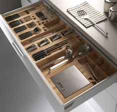 an open drawer with utensils and spoons in it on a counter top