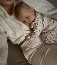 a baby wrapped in a blanket laying on top of a bed next to a woman