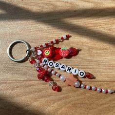 a keychain that says rosaro with beads and charms attached to it