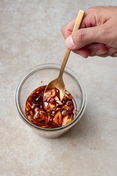 a hand holding a spoon over a bowl filled with food