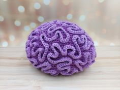 a crocheted purple ball sitting on top of a wooden table