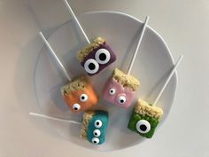 four marshmallows with googly eyes and sticks sticking out of them on a white plate