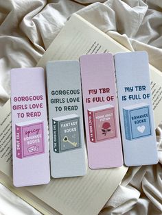 four bookmarks with different types of books on top of a white sheeted bed