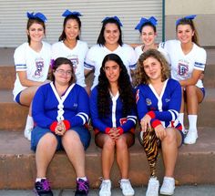 a group of young women sitting next to each other on the side of a building