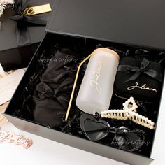 an open black box containing sunglasses, pearls and a bottle