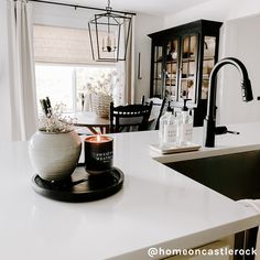 a white kitchen counter top with a candle on it and a vase next to the sink