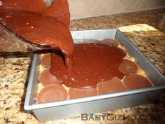 someone is spreading chocolate on top of some cookies in a pan with a spatula