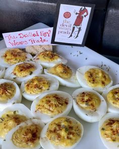 an assortment of deviled eggs on a white platter with a red sign that says the deviled egg wears rids