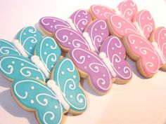 decorated cookies in the shape of butterflies on a white tablecloth with pink, blue and green icing