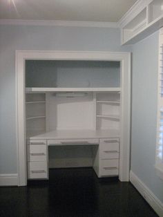 an empty white desk with drawers and shelves