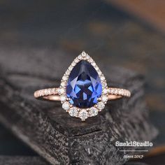 a blue sapphire and diamond ring sitting on top of a piece of wood with diamonds around it