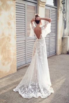 a woman in a white wedding dress standing on the street with her back to the camera