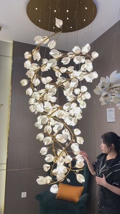 a woman standing in front of a chandelier with white flowers hanging from it