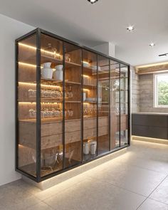 an empty room with glass doors and shelves filled with dishes on the wall, along with lights